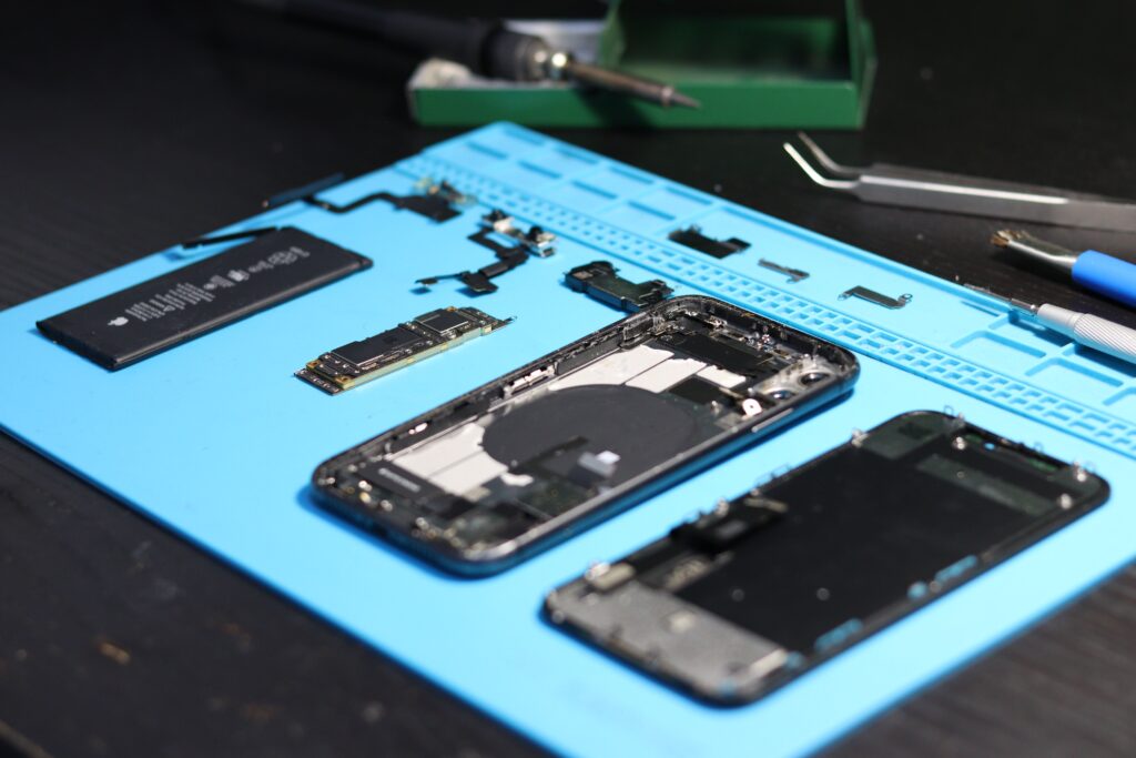 pexels-photo-31862953-31862953 Disassembled smartphone with tools on a workbench, emphasizing repair and technology.