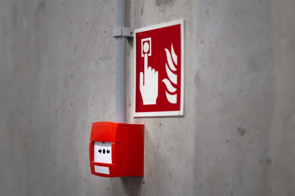pexels-photo-31470430-31470430 Red fire alarm button and sign on a concrete wall for emergency safety indoors.