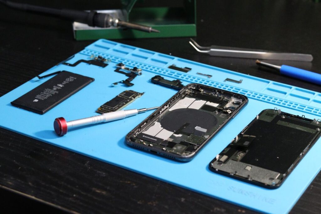 pexels-photo-31862950-31862950 Close-up of disassembled smartphone parts on a blue repair mat with tools.