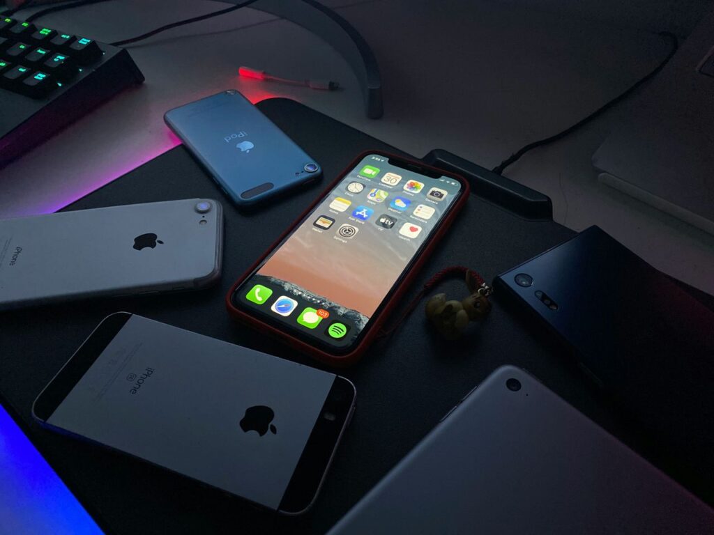 pexels-photo-32890115-32890115 Close-up of various Apple devices on a desk illuminated by dim light.