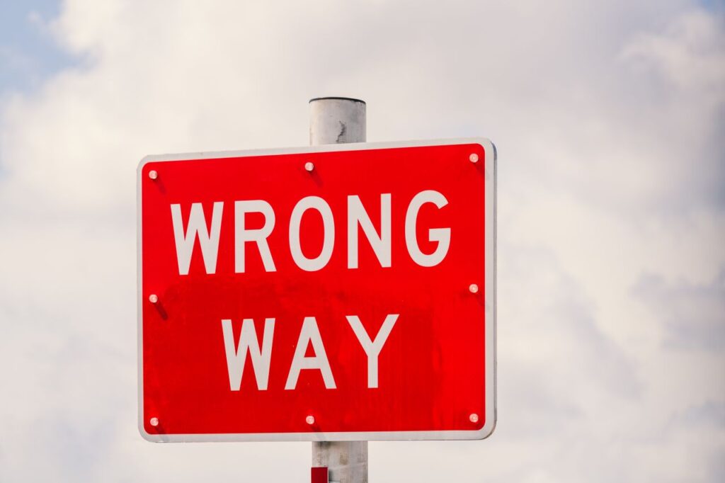pexels-photo-35113478-35113478 Clear image of a bright red 'Wrong Way' traffic sign against a cloudy sky in Miami, Florida.
