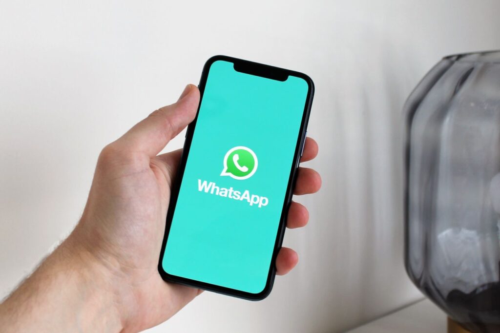 pexels-photo-4132538-4132538 Close-up of a hand holding a smartphone displaying the WhatsApp app screen.