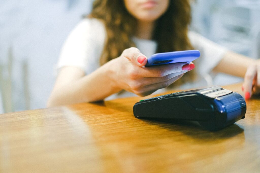 pexels-photo-4226272-4226272 A woman processes a contactless payment using her smartphone at a payment terminal.