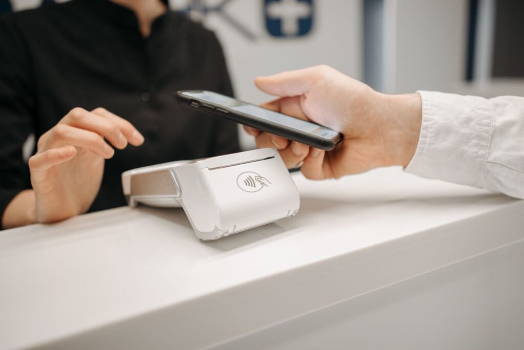 Person using a smartphone for contactless payment at a retail counter, highlighting cashless convenience.