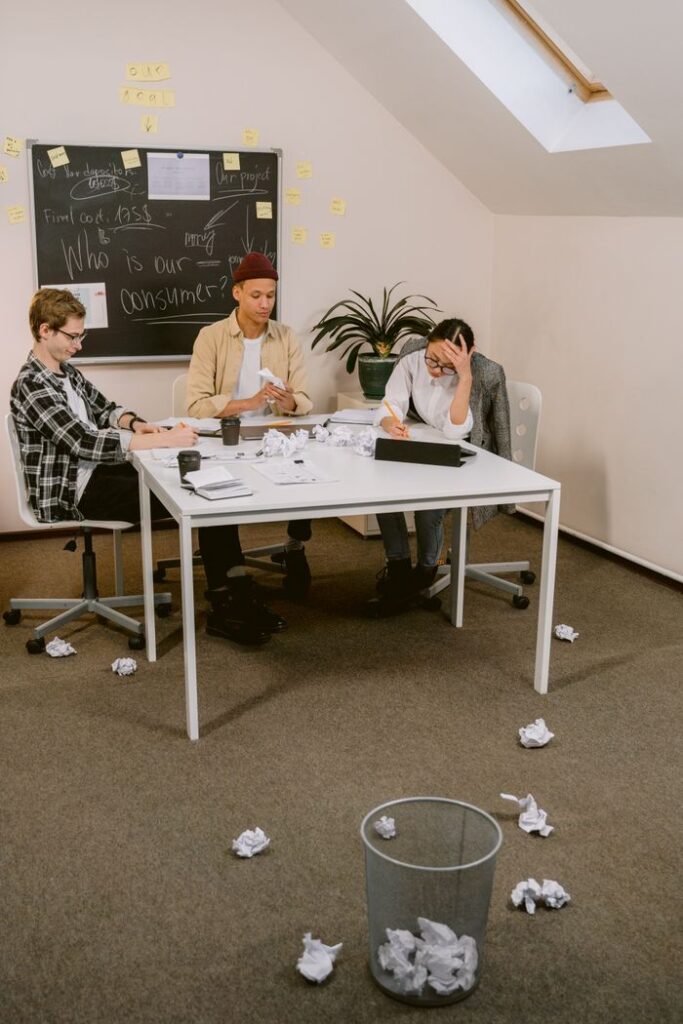 pexels-photo-6913296-6913296 Three colleagues brainstorming ideas in a cluttered office environment.