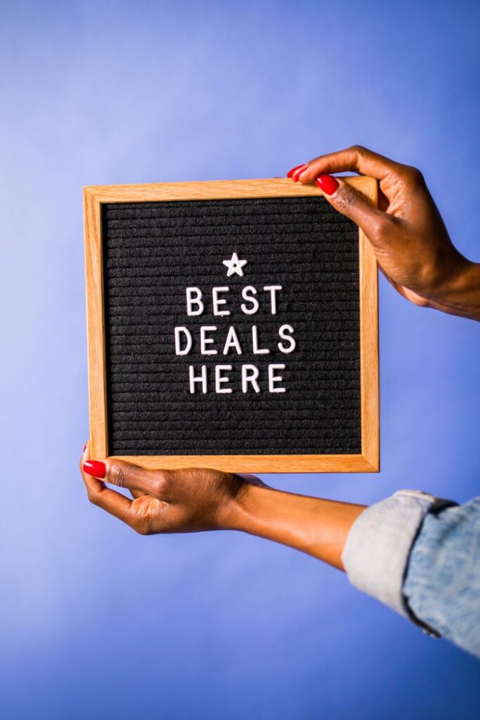 pexels-photo-7564195-7564195 Photo of hands holding a letter board with 'best deals here' on a blue background.