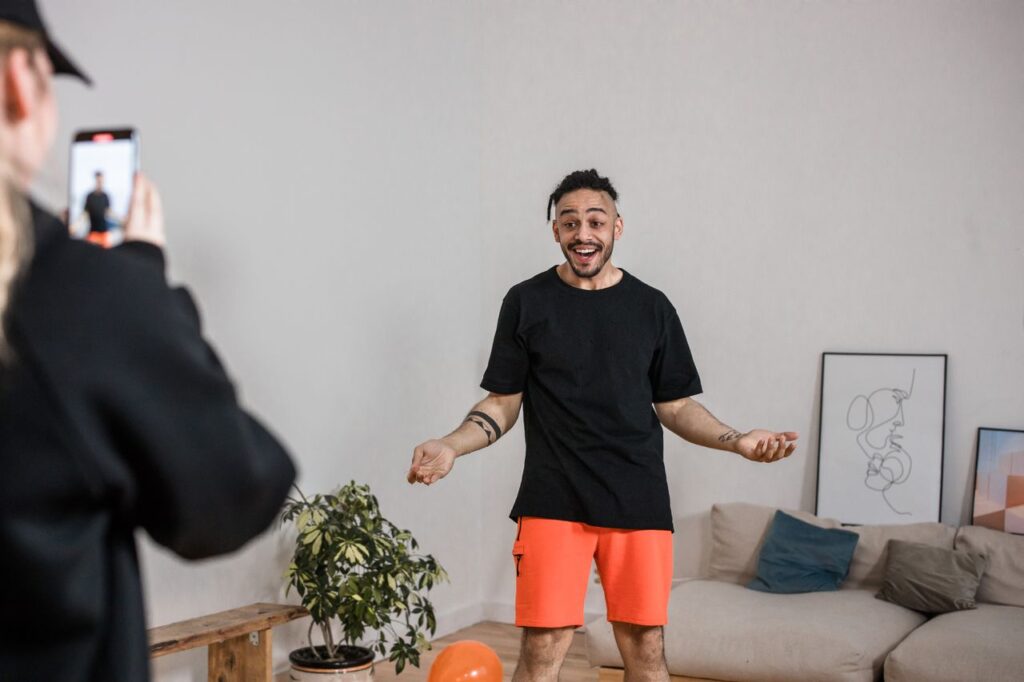 pexels-photo-8368745-8368745 Man in black shirt vlogging indoors with smartphone capturing lively expressions.
